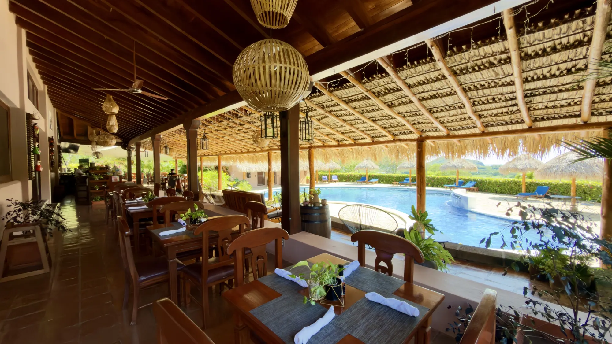 Terraza de Palermo's tables under the thatched roof, facing the pool