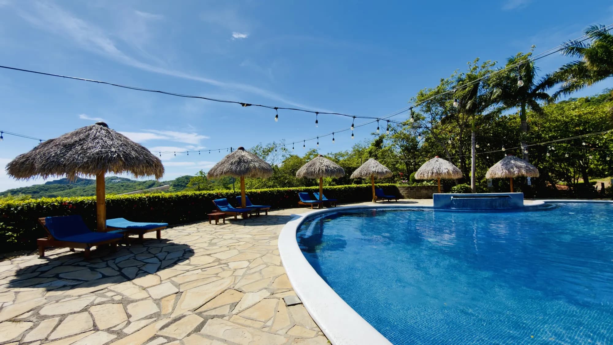 Stone pool deck with loungers and palapas
