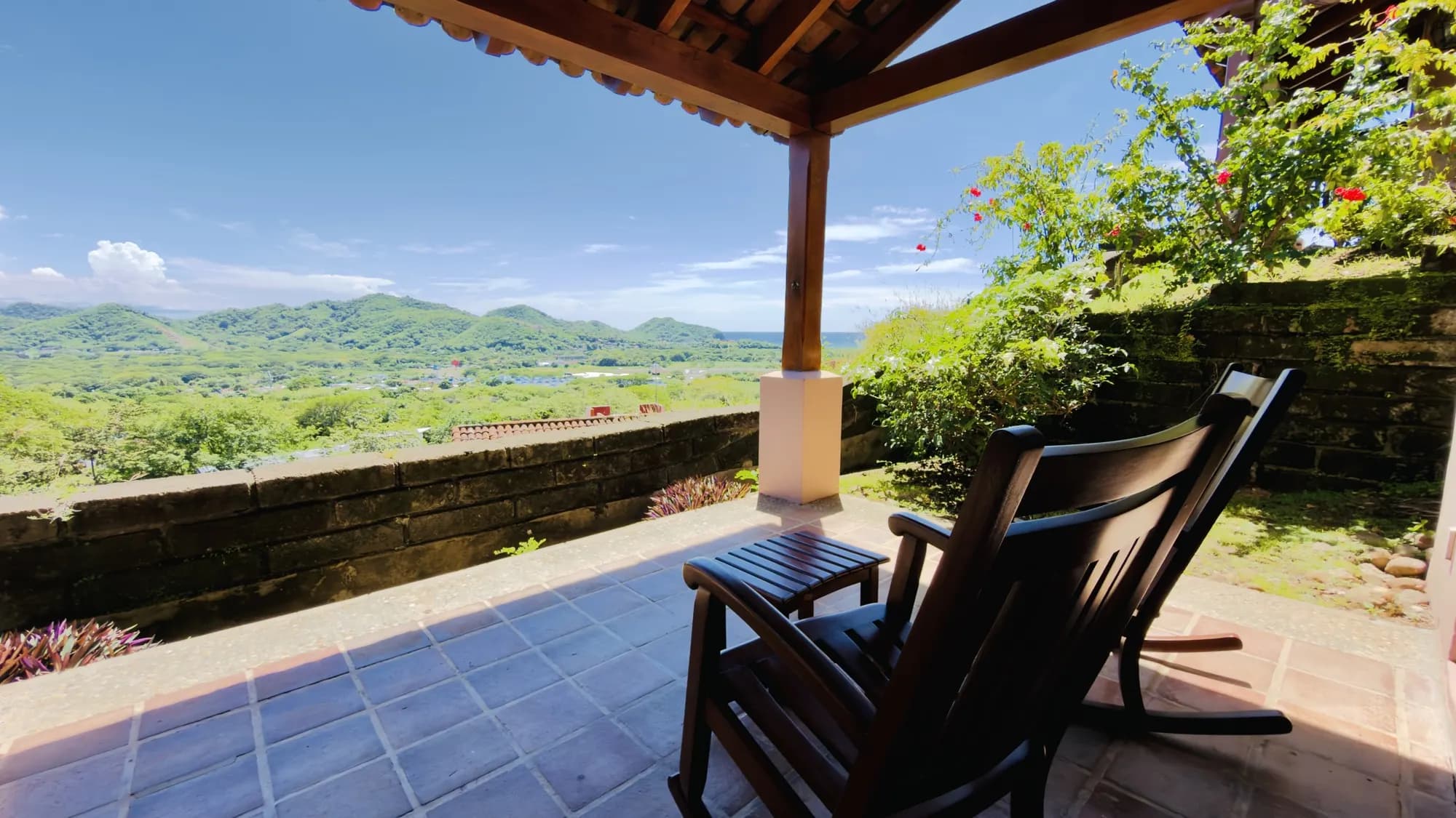A villa's covered terrace with a rocking chair and the valley below